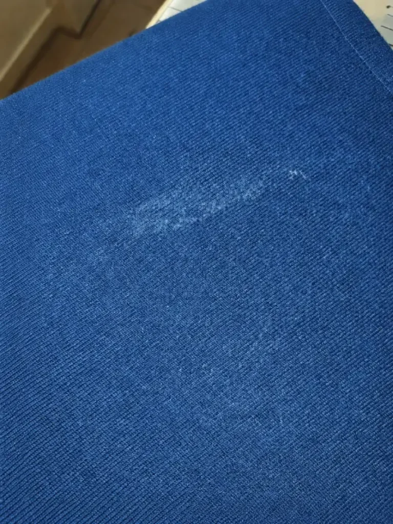 Marque blanchâtre laissée sur un tissu bordeaux après repassage